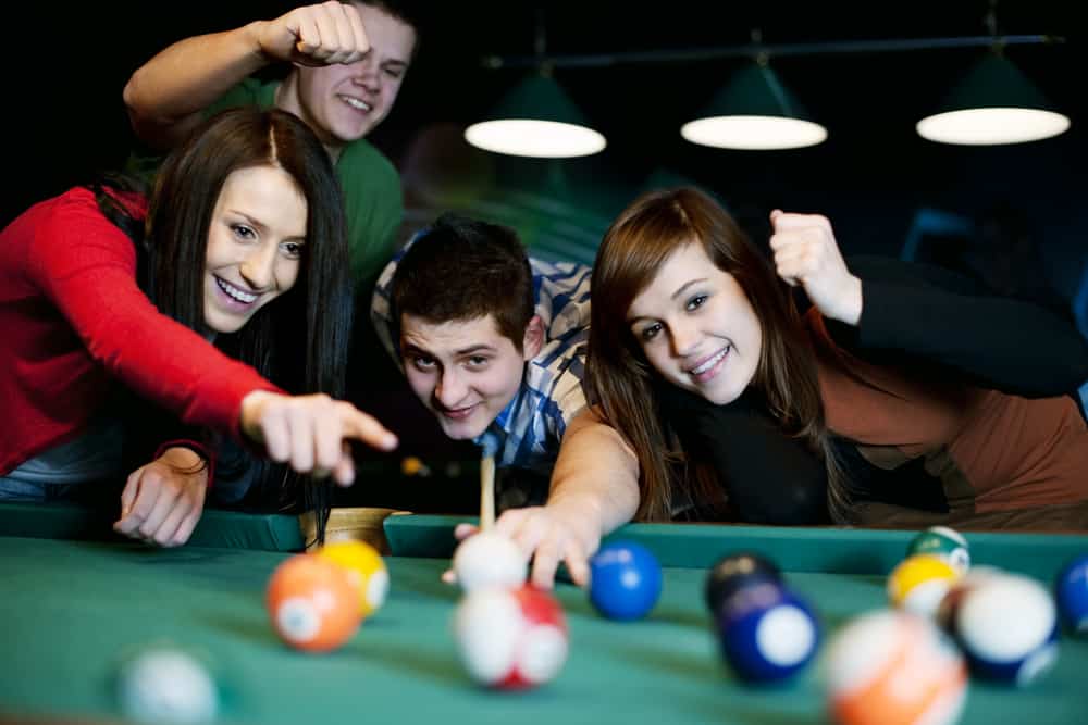 Group of men and women playing pool