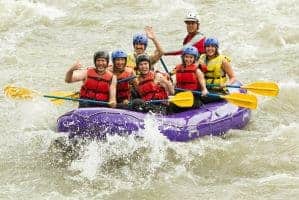 A family white water rafting on a river.