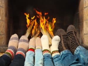 A family with their feet in front of the fireplace.