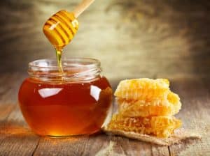 A jar full of honey, a dipper, and honeycomb.