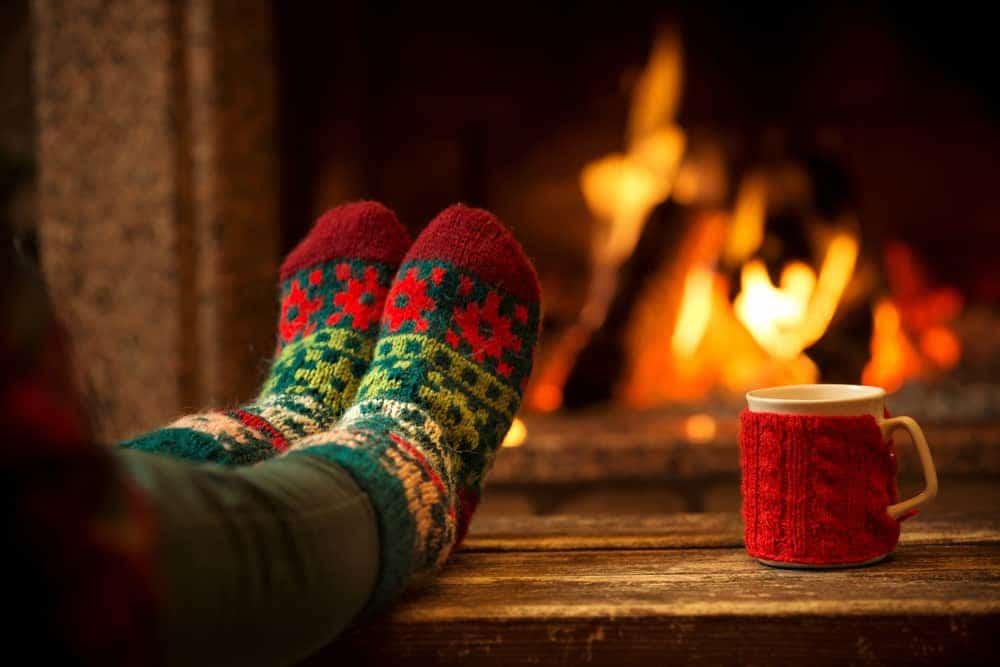 A woman warming her feet in front of the fireplace.