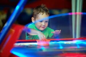 A young boy playing air hockey.