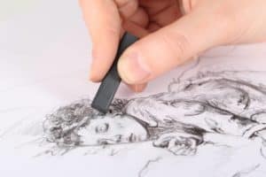 Closeup photo of a hand drawing with charcoal.